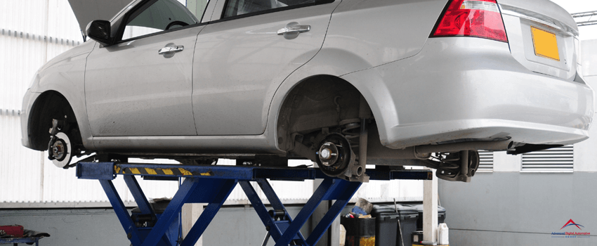 A car without wheels inside an auto repair shop.