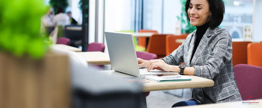 A content writer woman with Buttoned Blazer outfit, smiling while looking at her laptop.