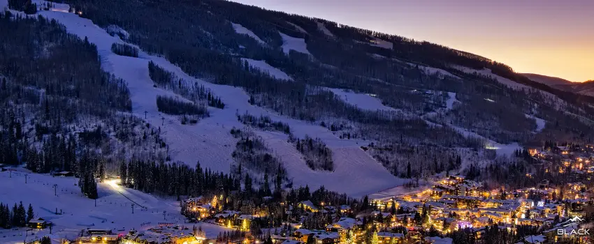 Village below a snowy mountain slope during dawn time.