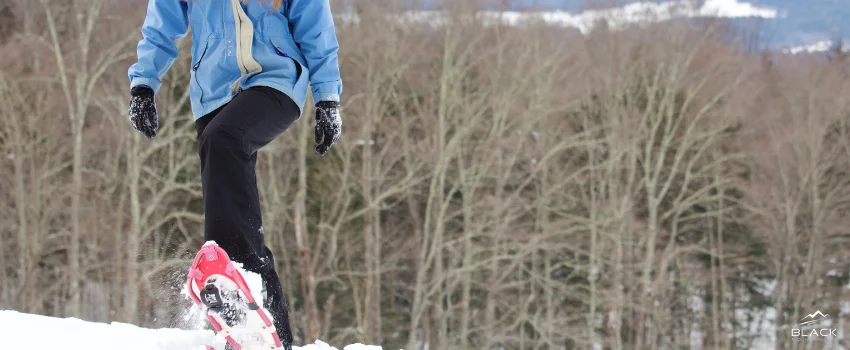 A man wearing a winter garments and a red snowshoes.