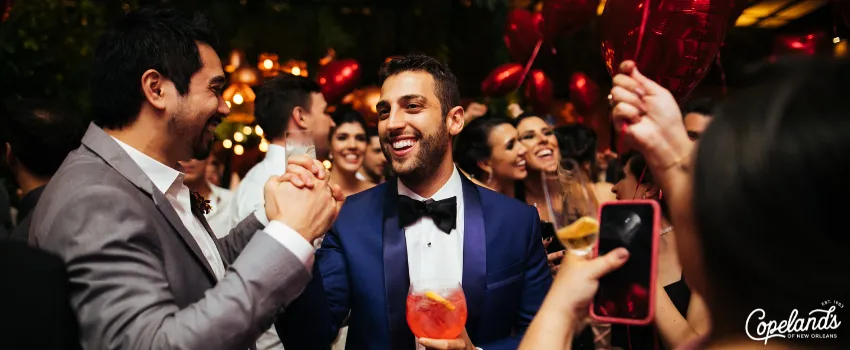 JDC - Groom holding a cocktail in the middle of a crowd